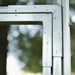 Galvanized metal greenhouse frame corner with rivets and bolts. Durable construction for outdoor garden structures.