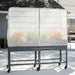 Vego Garden dark gray mobile raised garden bed with white mesh greenhouse cover, protecting vibrant plants on wheels.