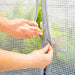 Hands zipping and velcro fastening transparent grid greenhouse cover. Portable plant protection, gardening.